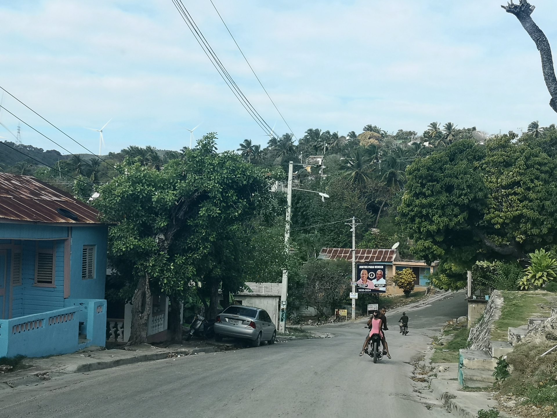 Mototaxi on a Dominican Republic town street with blue house and palms