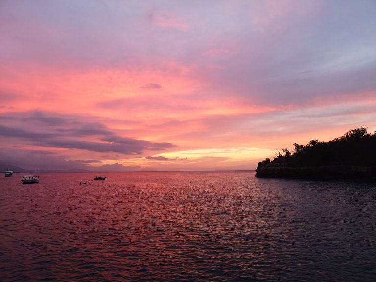 dramatic pink purple sunset boats rocky headland sosua