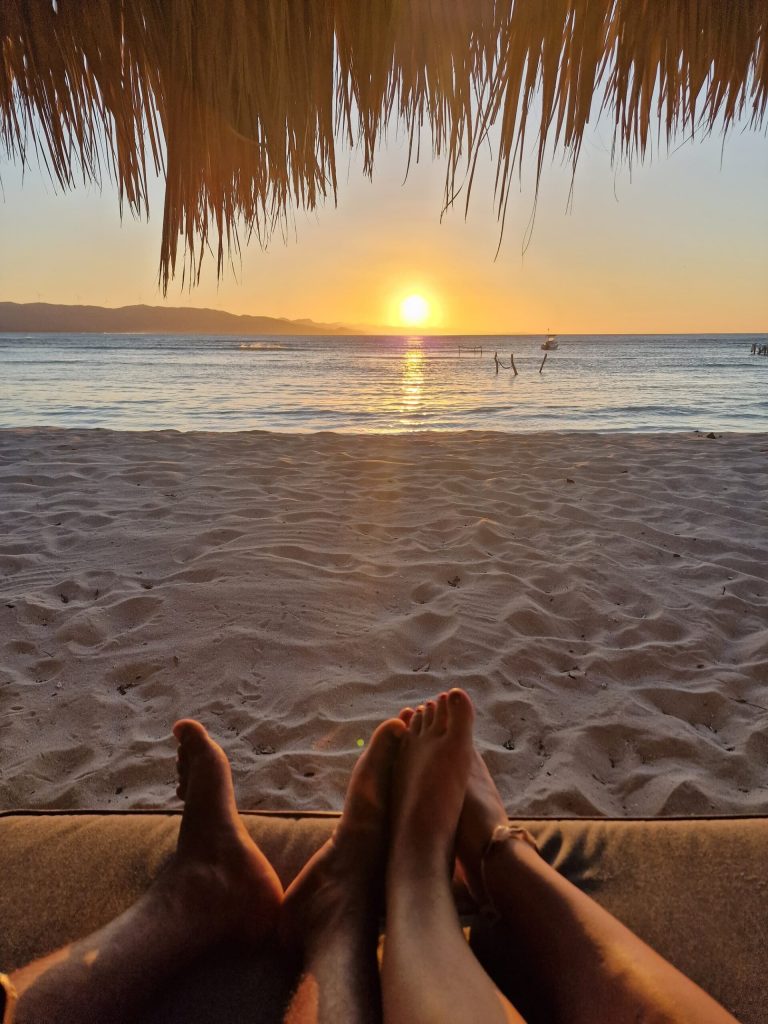 feet on pier sunset golden water punta rucia lodge